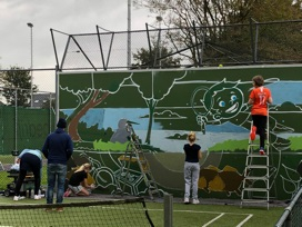 Kinderen helpen de verfdokter bij het tennismuurtje